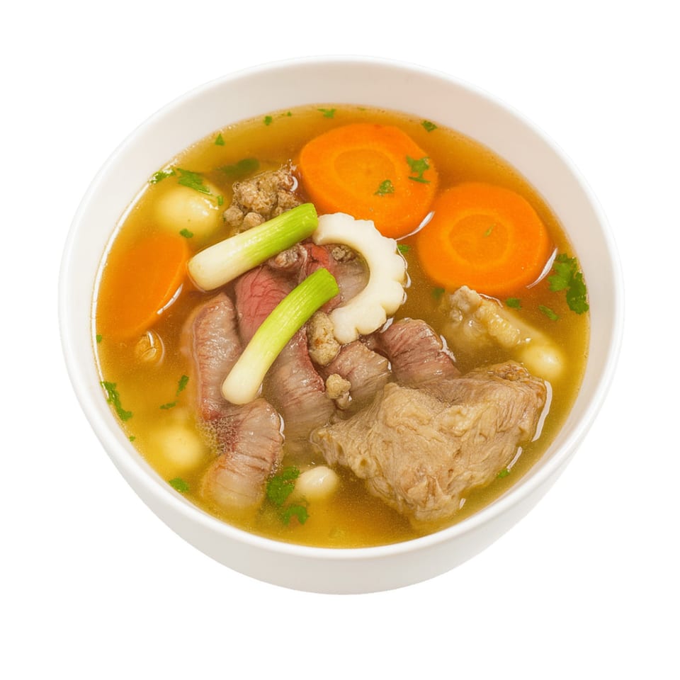 A bowl of Vietnamese soup with beef, carrots, green onions, and other vegetables.