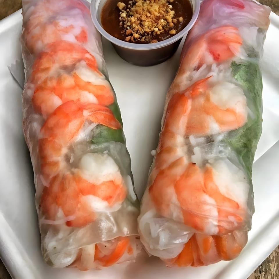 Two fresh Vietnamese spring rolls with shrimp and greens, served with peanut dipping sauce.